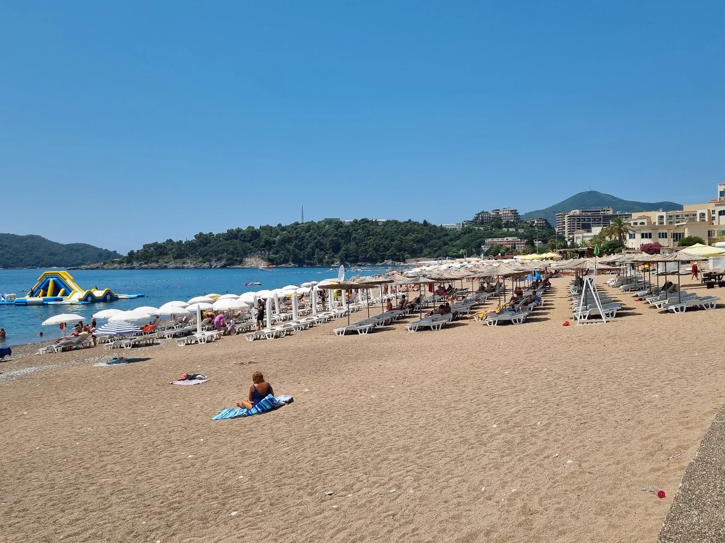 Swimmers and a floating aqua-park in the turquoise water off Bečići Beach