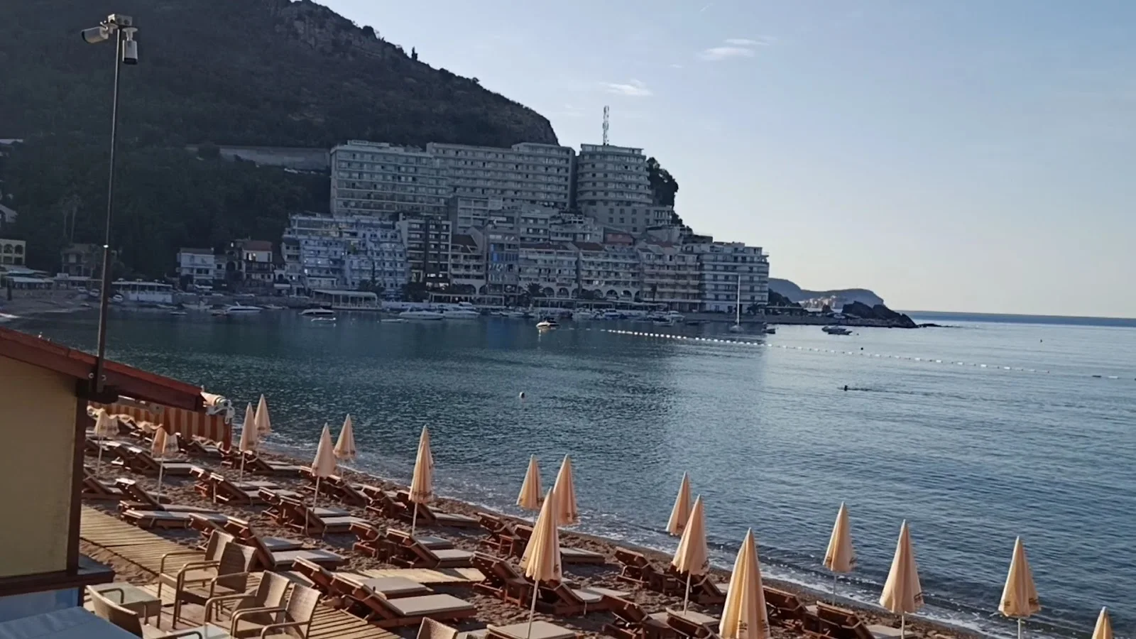 Sun loungers and umbrellas along the seaside promenade at Bečići with the resort behind