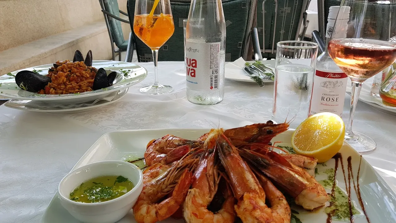 Grilled prawns and seafood risotto on a garden-terrace table at Restaurant Atlantic in Rafailovići