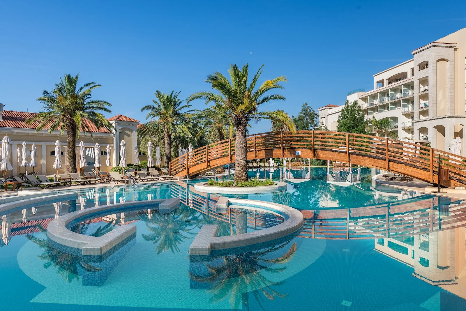 Palm-fringed pool with a wooden bridge at the Splendid resort in Bečići
