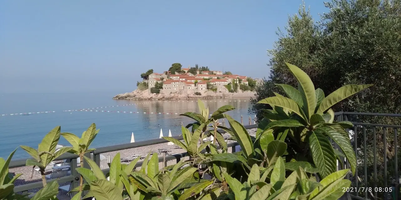 The fortified islet of Sveti Stefan seen across the bay from a terrace above the beach