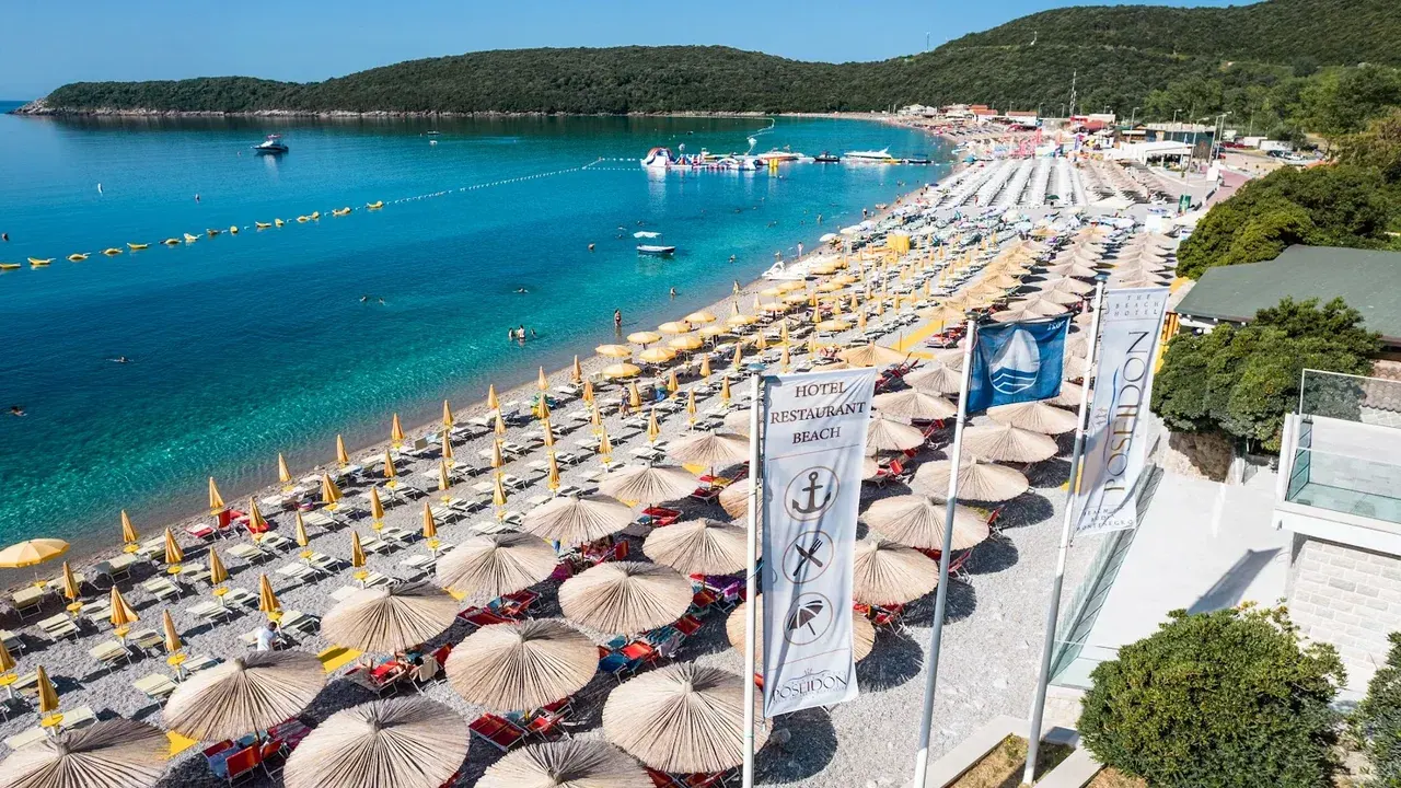 Aerial view of a sandy Adriatic beach lined with thatched umbrellas and turquoise shallow water
