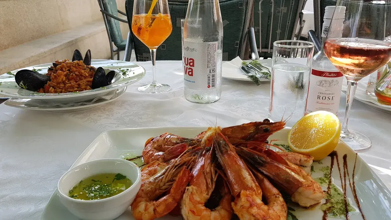 Grilled prawns and seafood risotto on a garden-terrace table at Restaurant Atlantic in Rafailovići