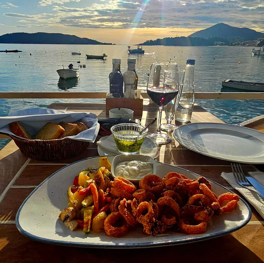 Plate of fried calamari on a seafront table at Restaurant Porat in Rafailovići at sunset