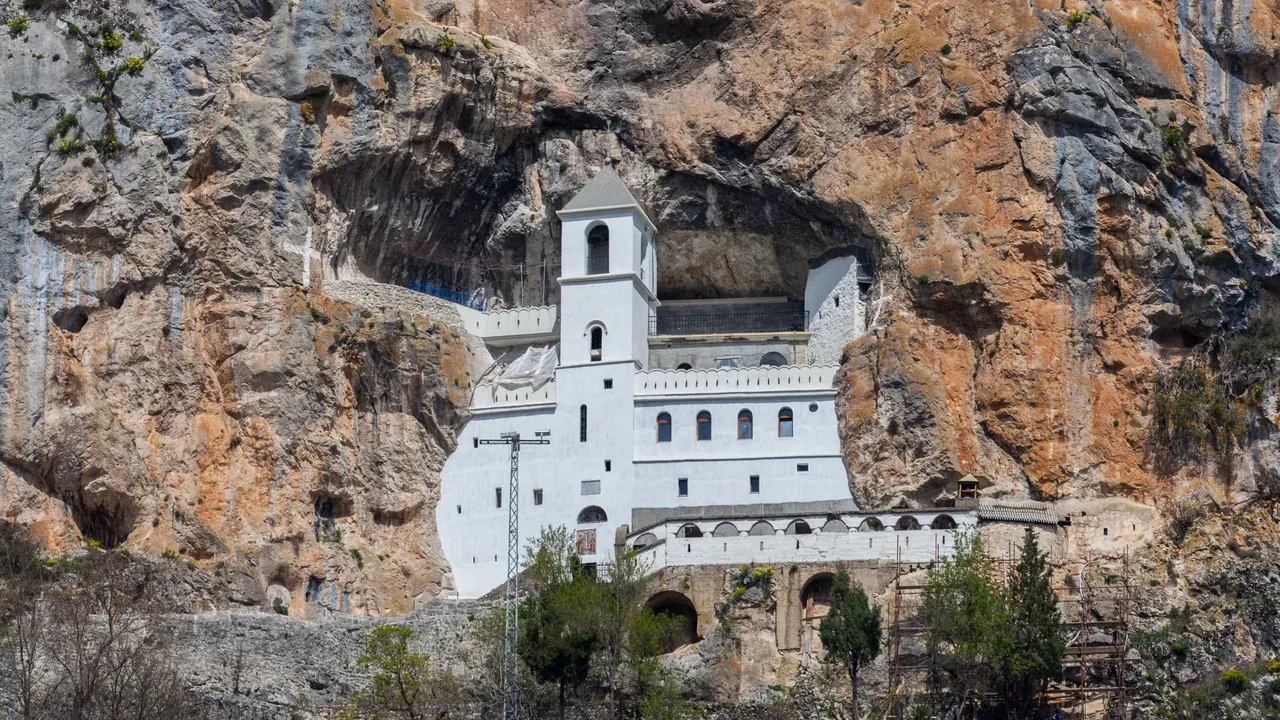 The whitewashed Ostrog Monastery set into a near-vertical grey cliff in Montenegro's interior