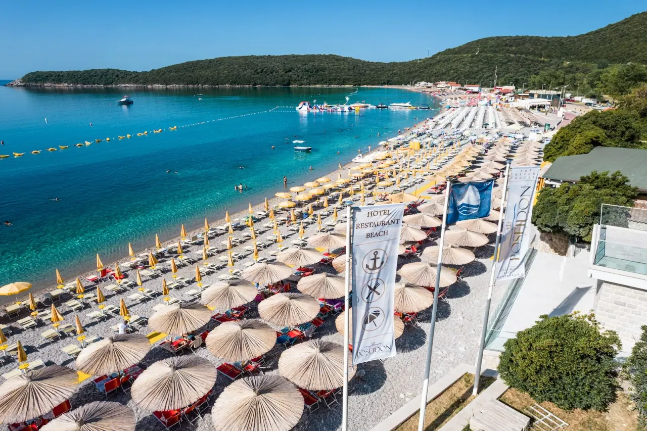 Aerial view of Hotel Poseidon's beach with thatched umbrellas and turquoise water