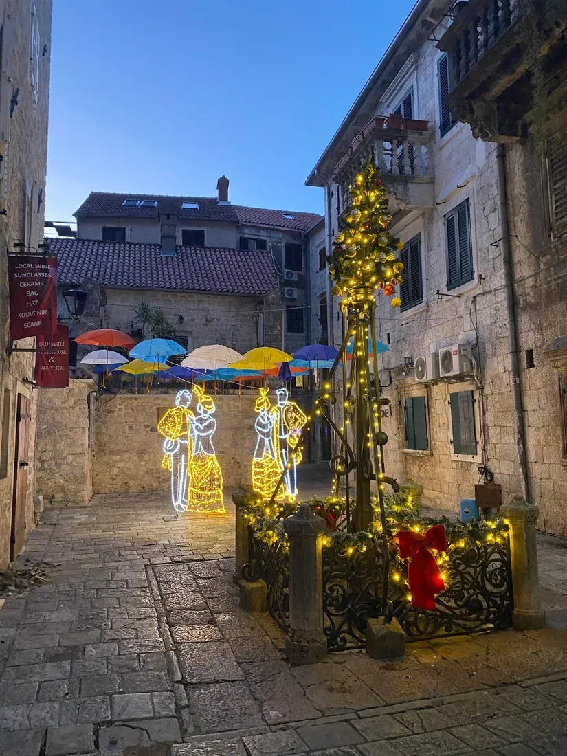 A lantern-lit lane in Kotor's medieval old town at dusk