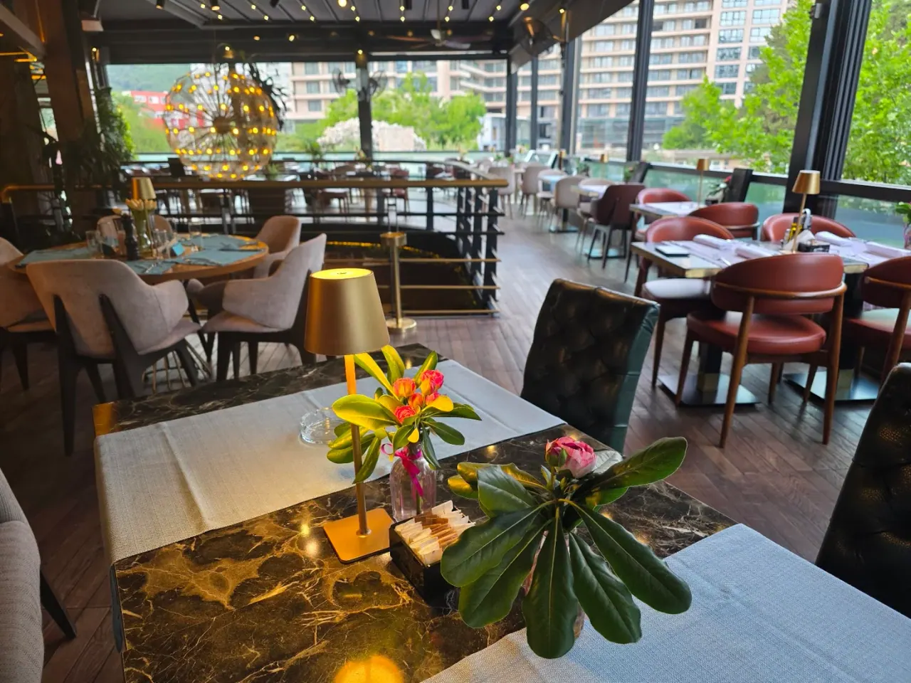 Leafy terrace dining room with warm lighting at Perla Restaurant & Club in Bečići