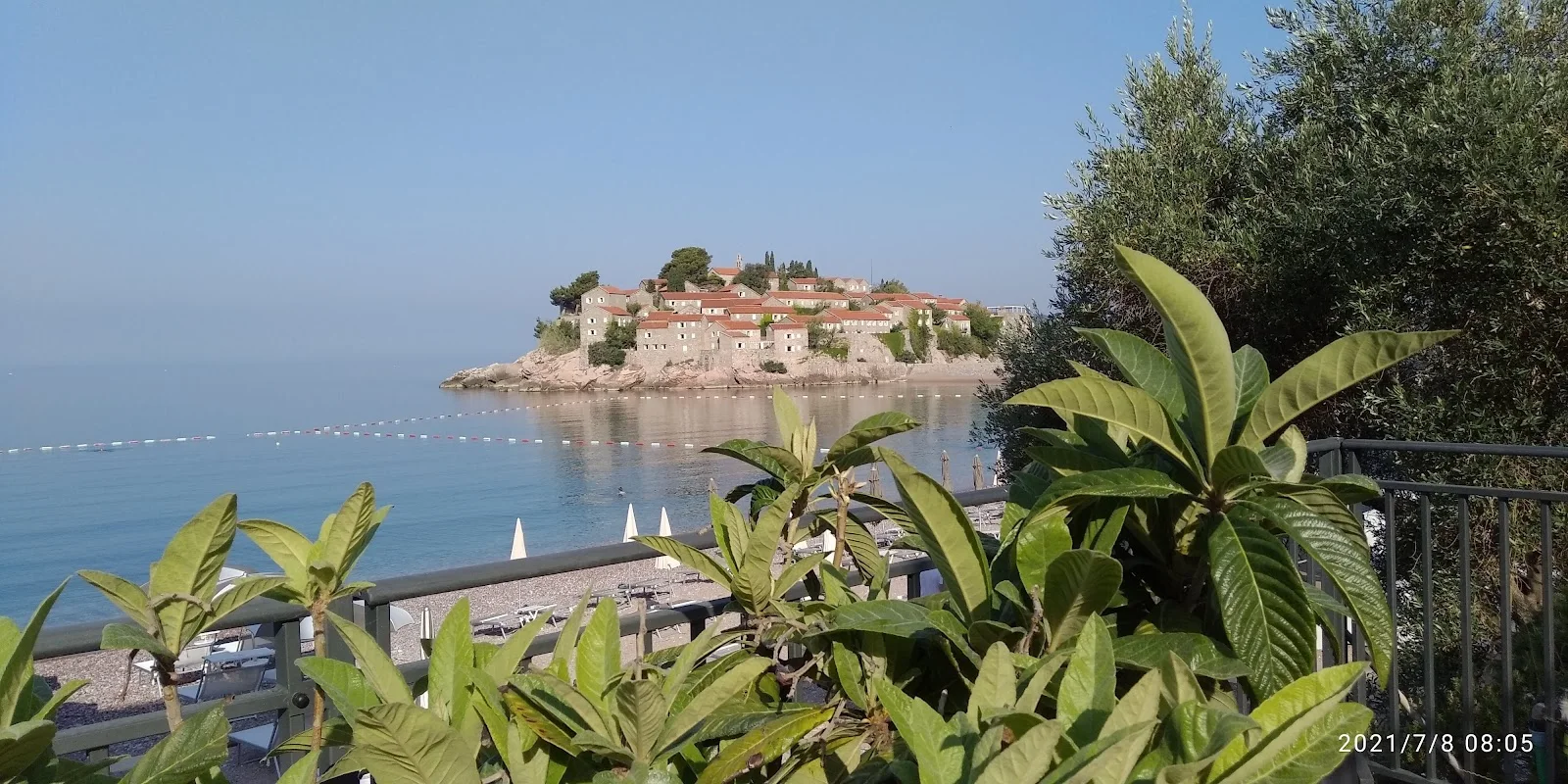 The fortified islet of Sveti Stefan seen across the bay from a terrace above the beach