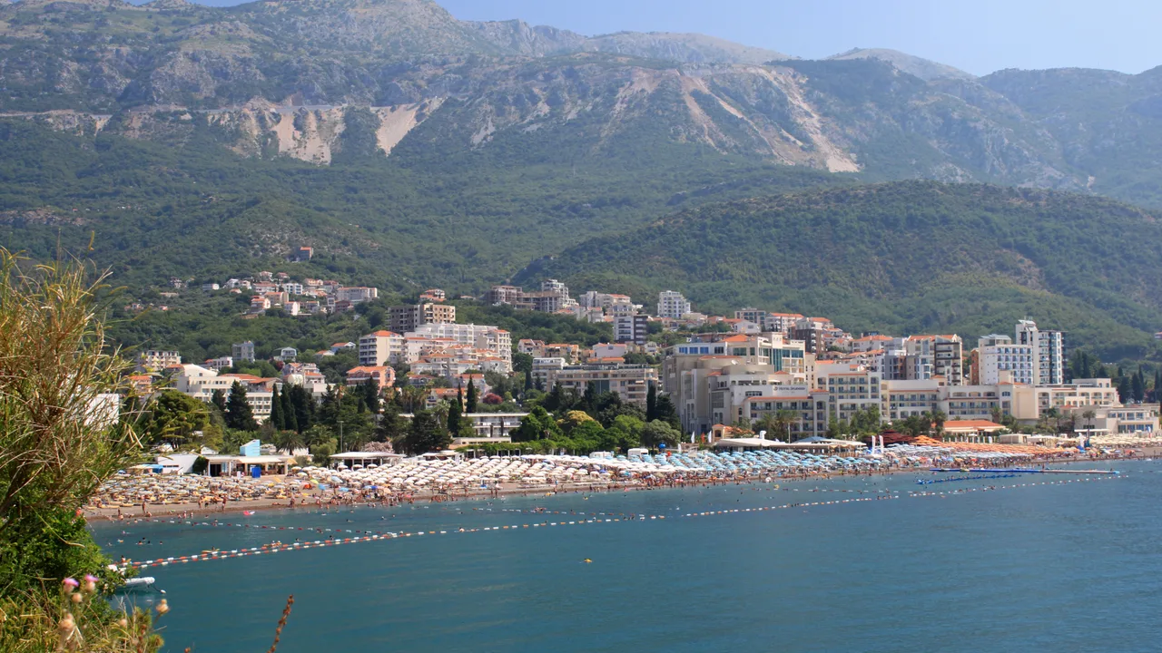 The long umbrella-lined crescent of Bečići beach below the coastal mountains, Montenegro