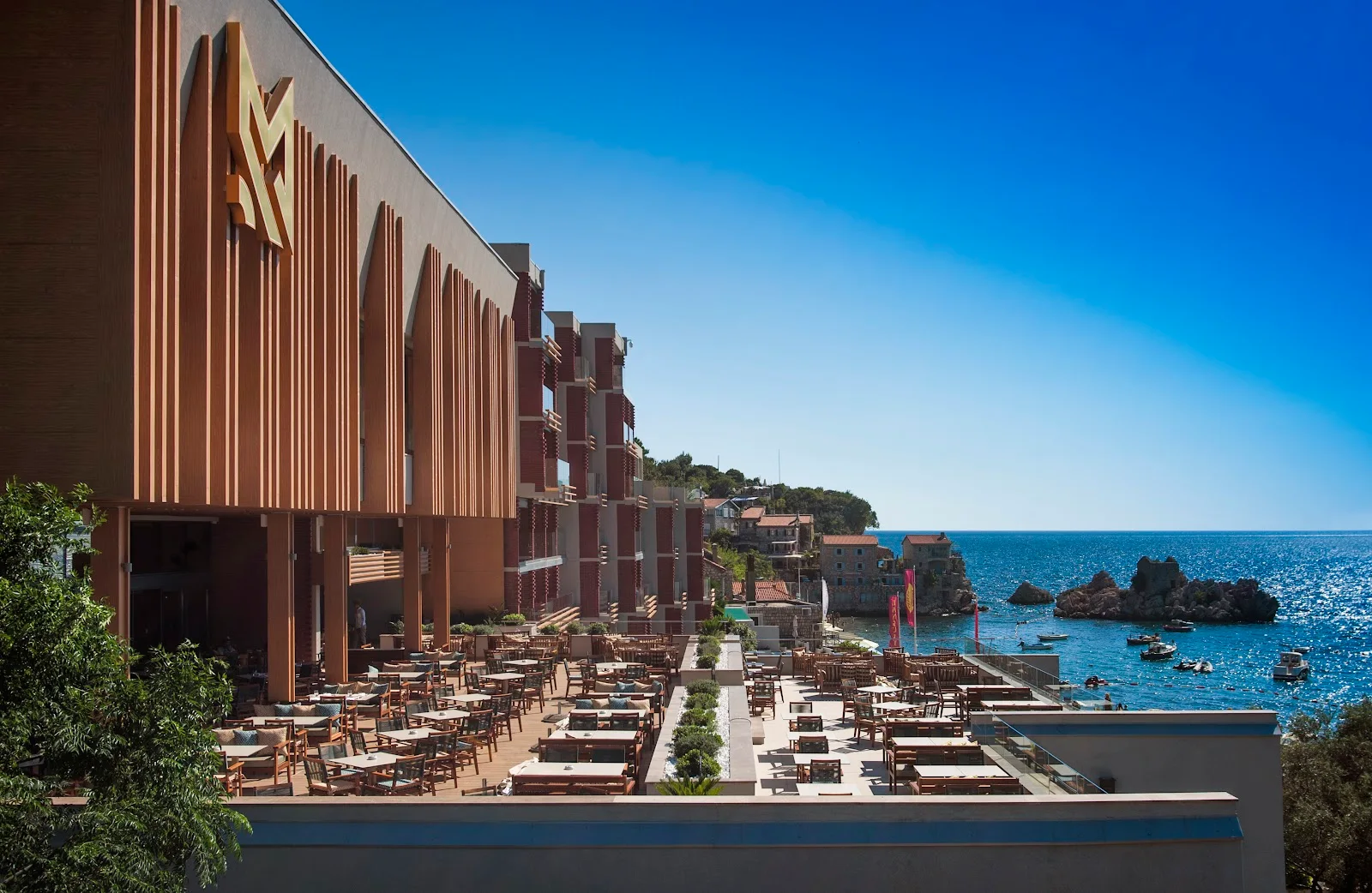 The Maestral Resort facade with its gold M emblem above a sea-view terrace at Pržno