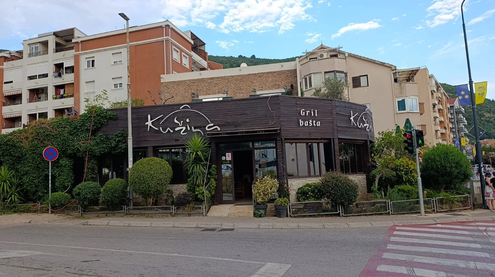 The dark-timber corner façade and garden terrace of Kužina grill house in Budva under the Gril bašta sign