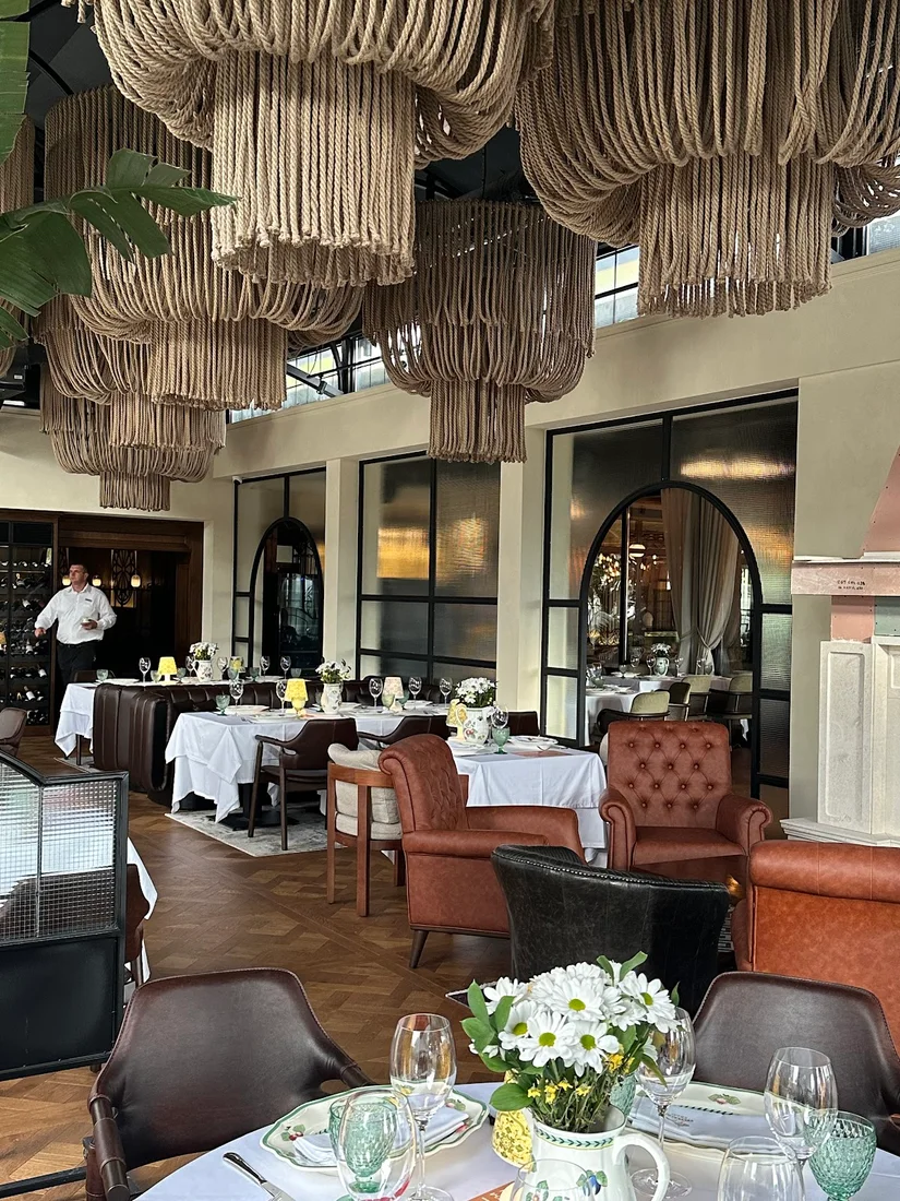 Polished dining room with rope chandeliers, leather armchairs and white-linen tables at Malo Ribarsko Selo in Budva