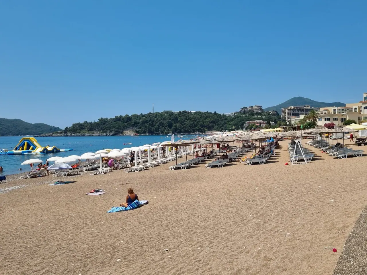 Swimmers and a floating aqua-park in the turquoise water off Bečići Beach