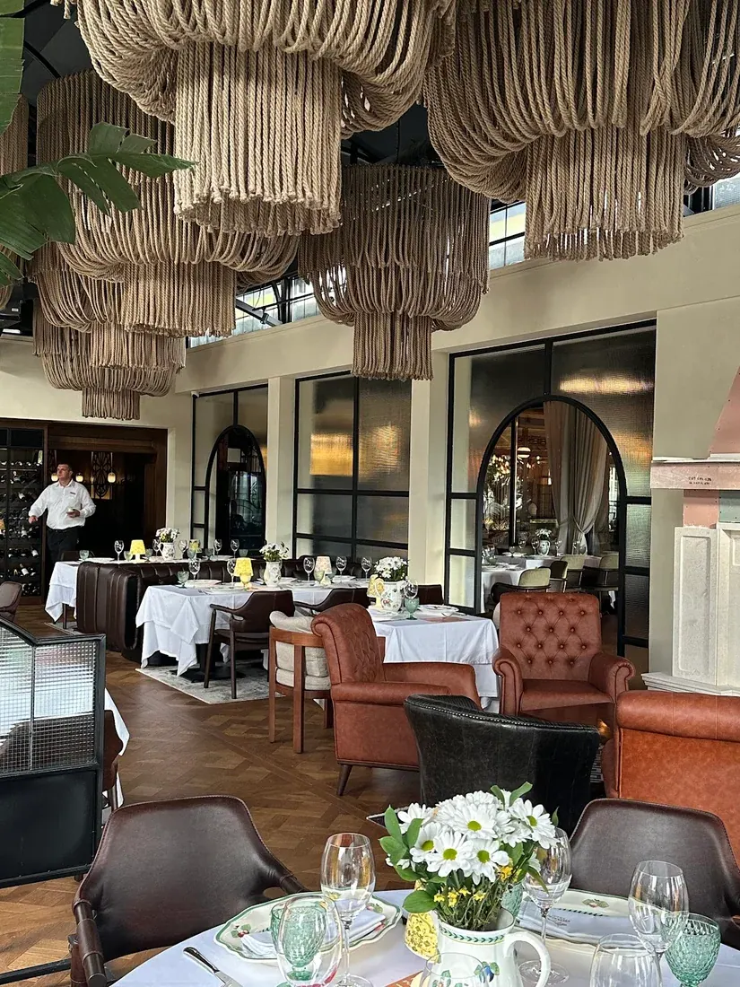 Polished dining room with rope chandeliers, leather armchairs and white-linen tables at Malo Ribarsko Selo in Budva