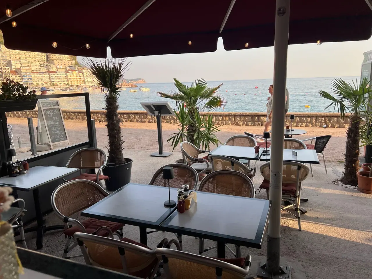 String-lit seafront terrace with umbrellas looking over the beach and bay at Restaurant Tulip in Rafailovići